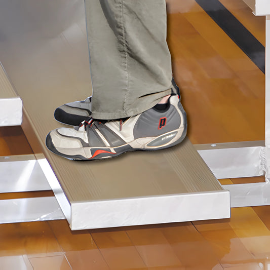 Person wearing sneakers standing on indoor bleacher seats in a gym.