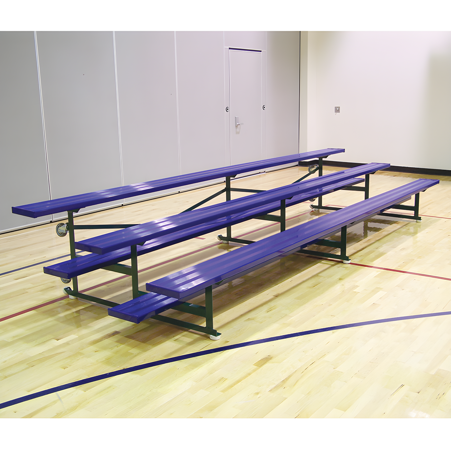 Blue metal bleachers on gymnasium wooden floor with gray walls.