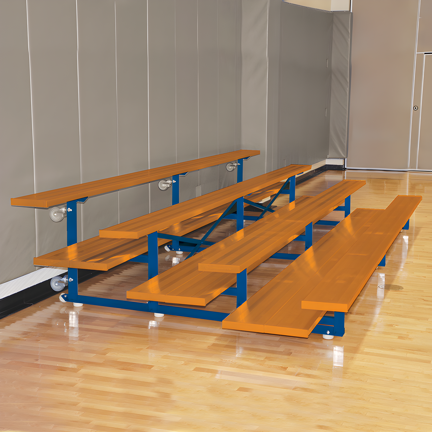 Orange and blue bleachers in gymnasium with wooden sports flooring.