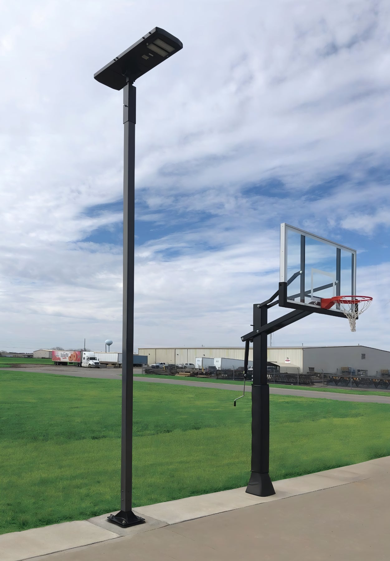 Outdoor basketball hoop with First Team Solar Court Light mounted on tall pole beside court