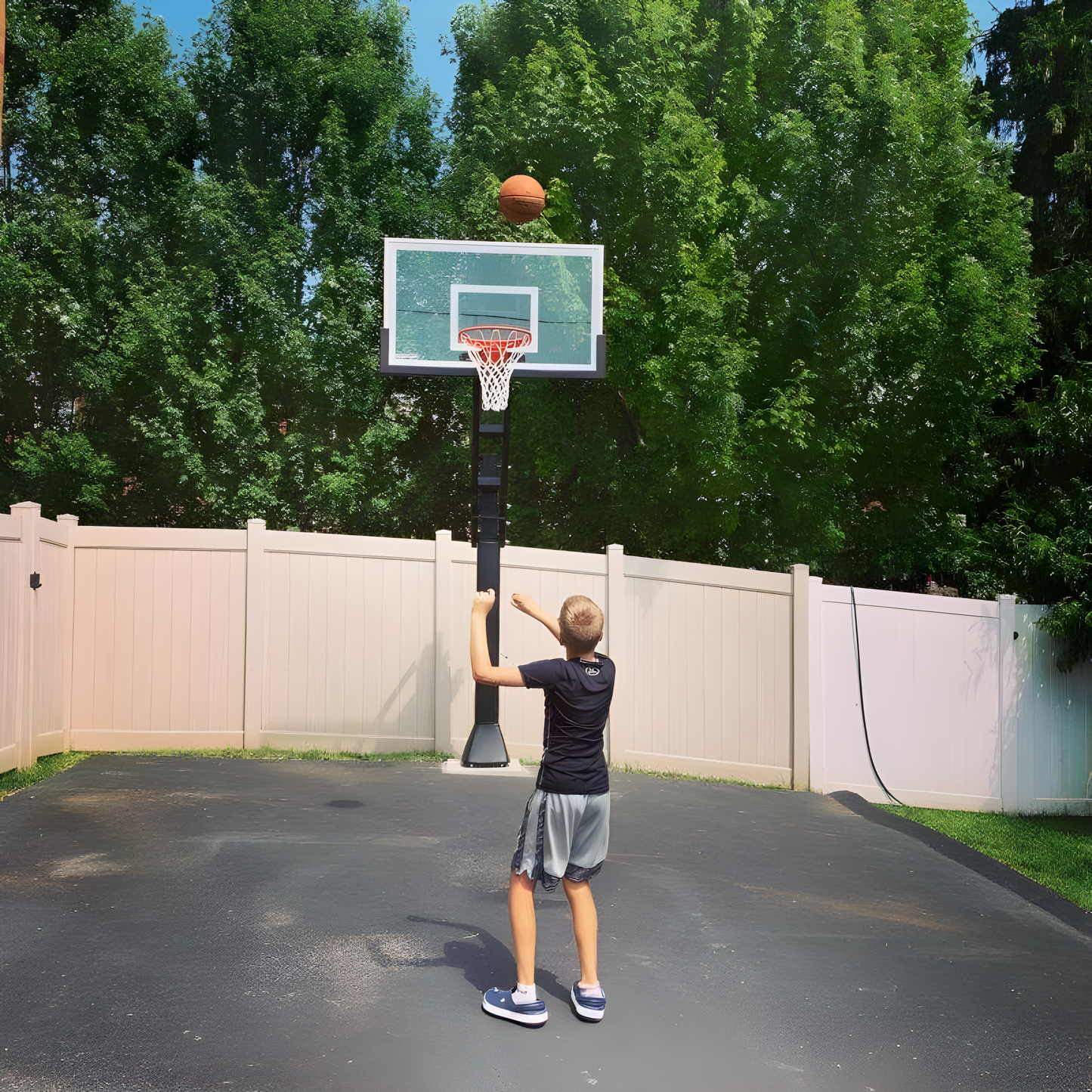 Boy shooting basketball on Ironclad In Ground Basketball Hoop in residential driveway