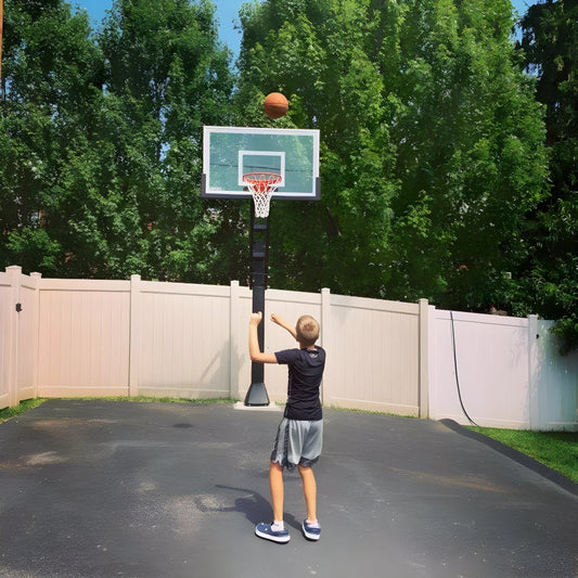 Boy shooting basketball on Ironclad In Ground Basketball Hoop in residential driveway