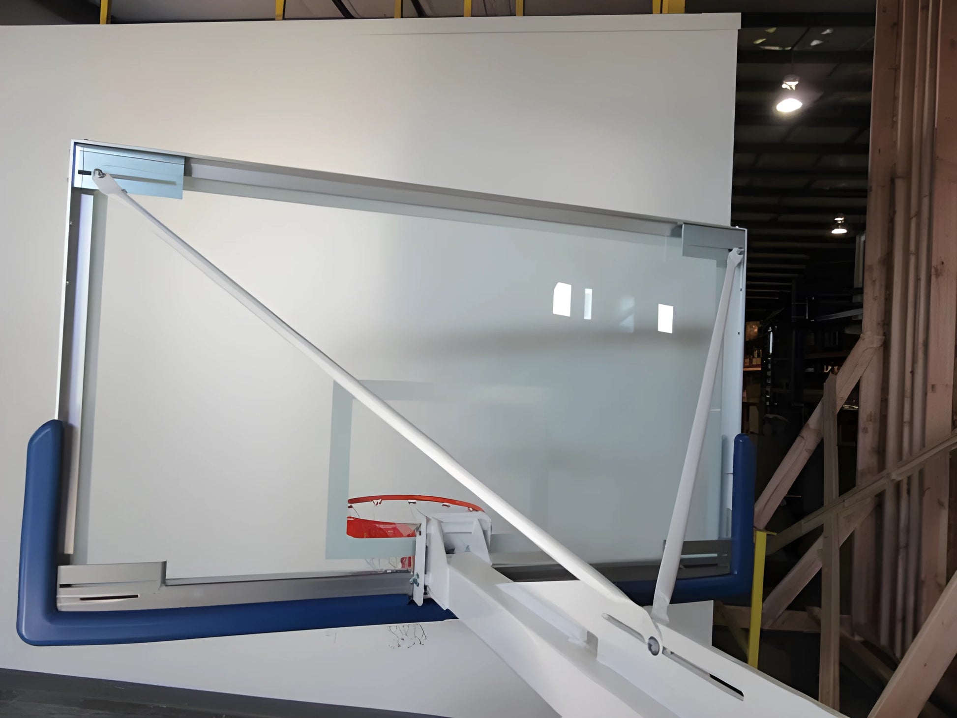 FIRST TEAM Portable Basketball Hoop with clear backboard and red rim in indoor warehouse setting