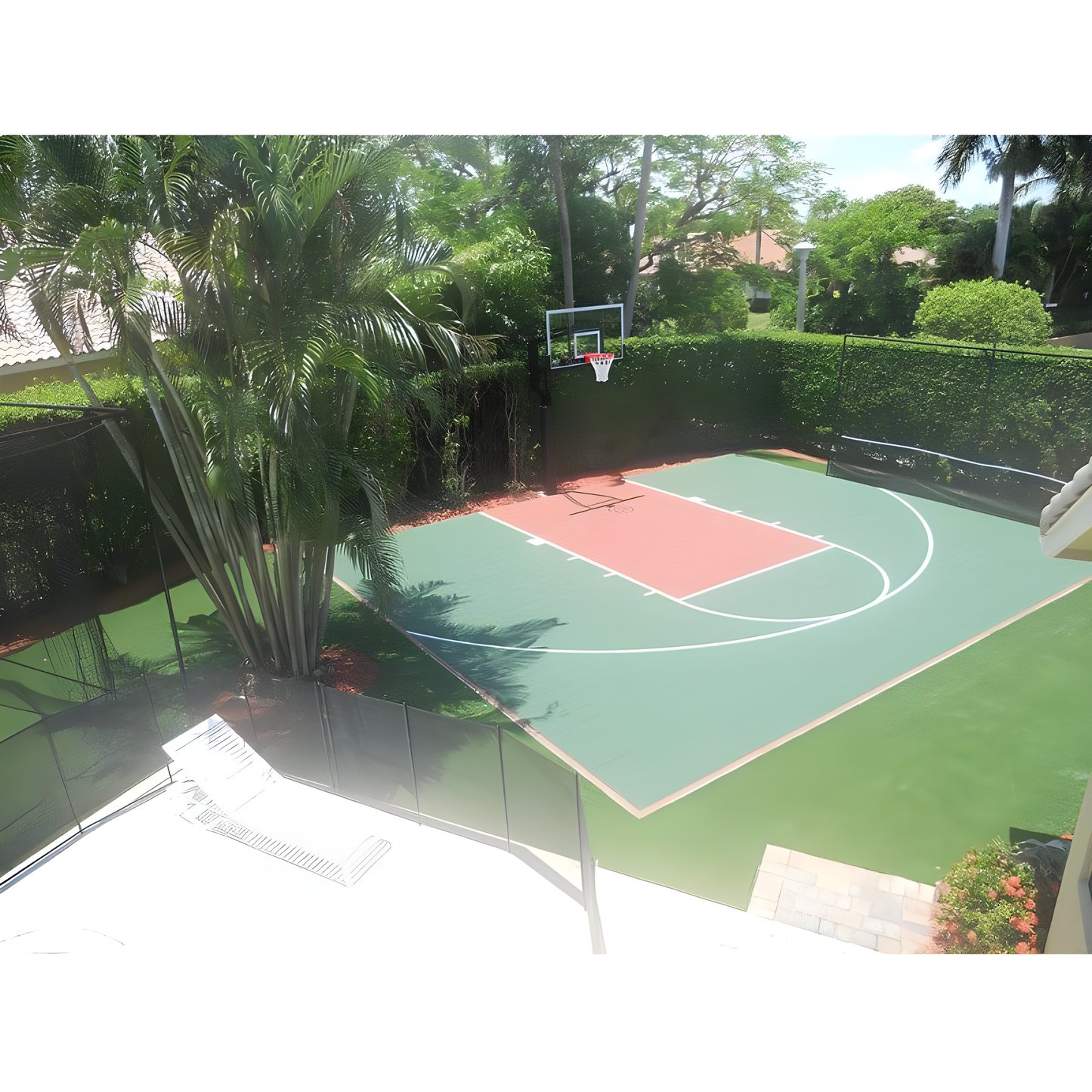 Jaypro outdoor basketball hoop installed on a residential green and red court surrounded by palm trees and hedges
