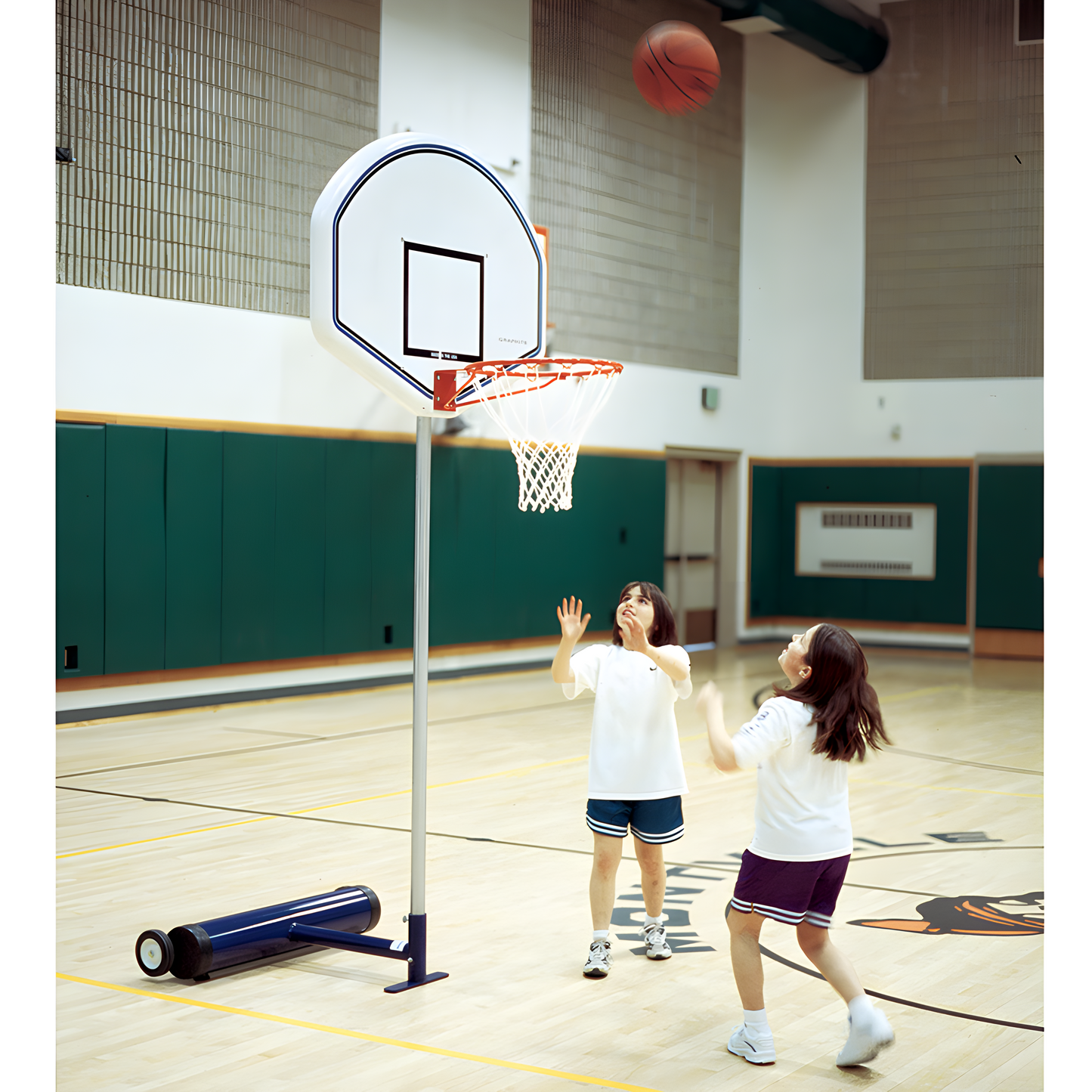 Children playing basketball indoors with Jaypro portable basketball hoop on gym court