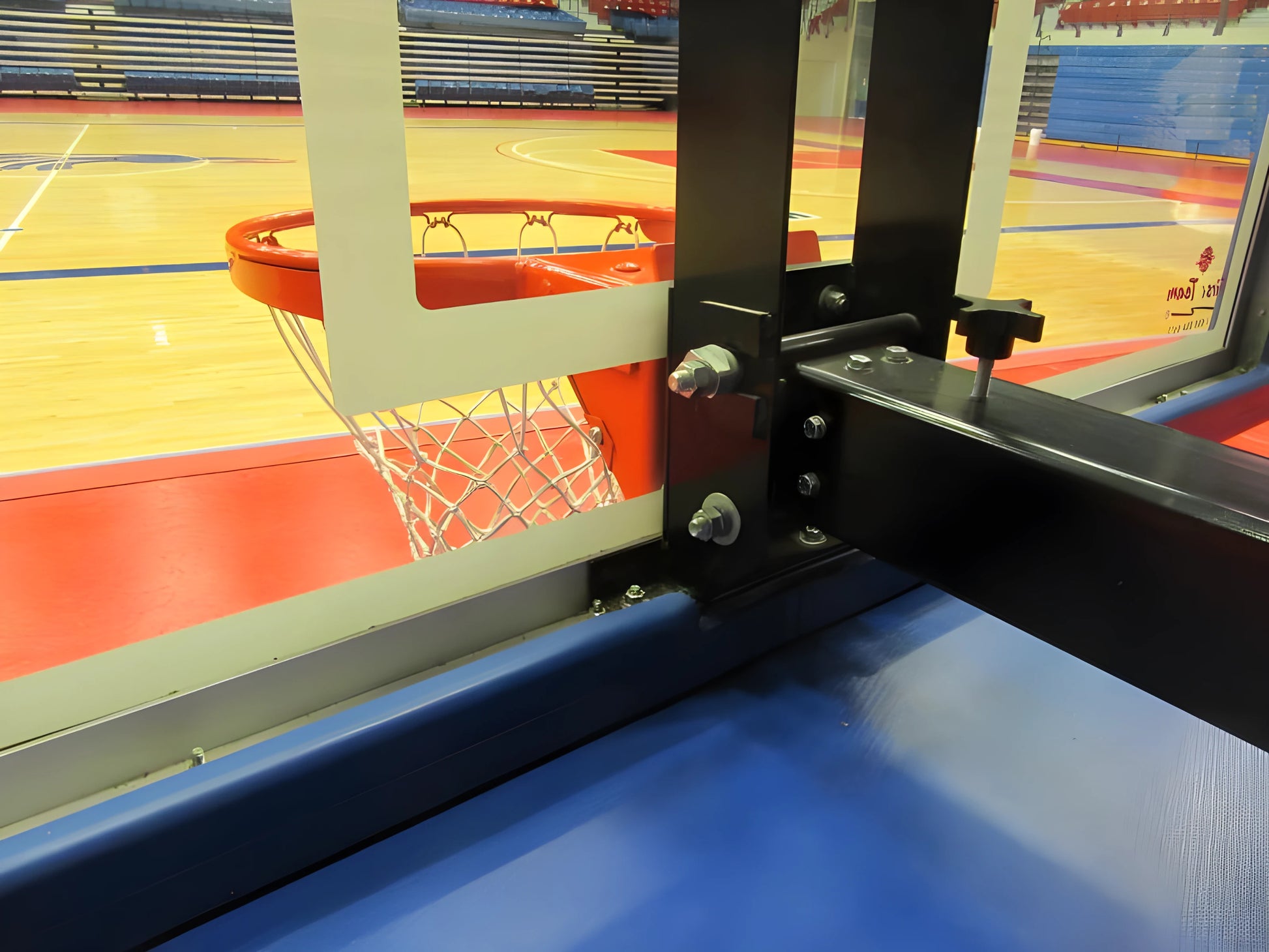 Close-up of FIRST TEAM portable basketball hoop mounting bracket and backboard in indoor gym