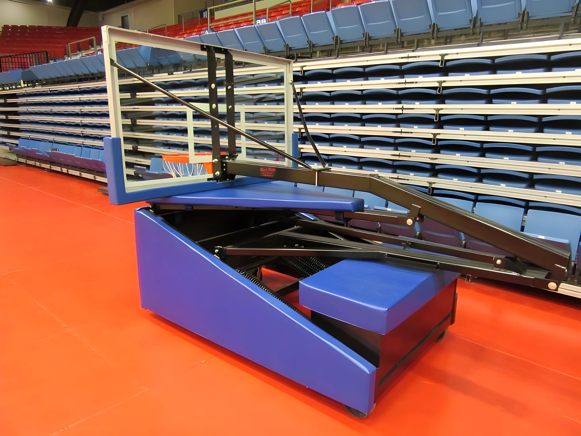 FIRST TEAM portable basketball hoop with glass backboard and blue base on indoor court