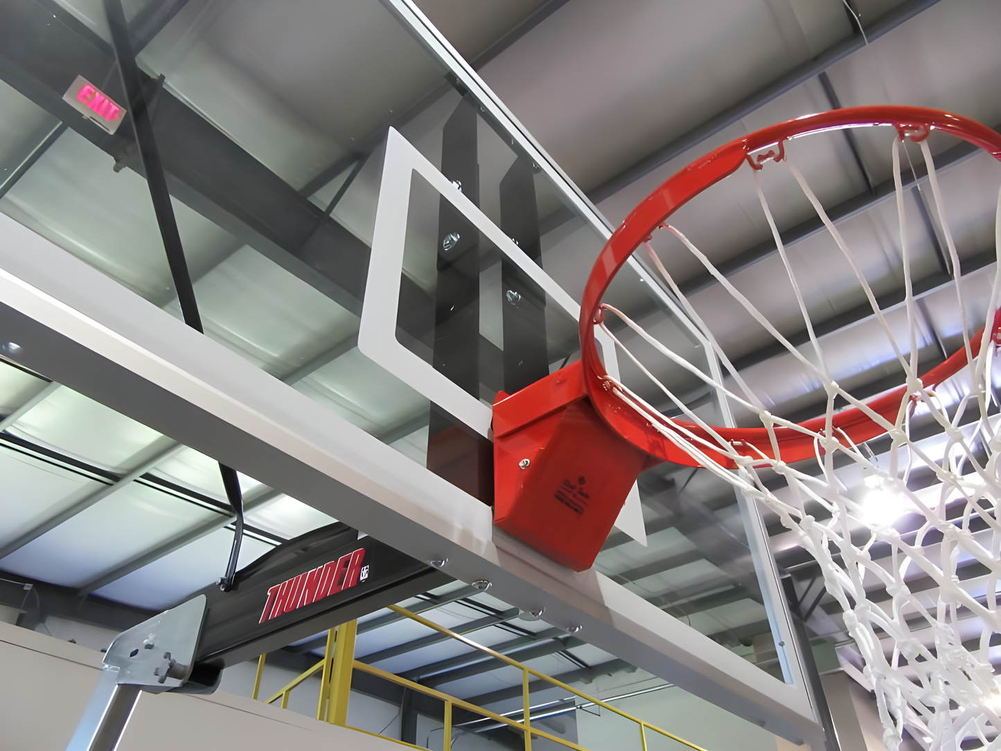 FIRST TEAM portable basketball hoop with clear backboard and red rim in indoor gym setting