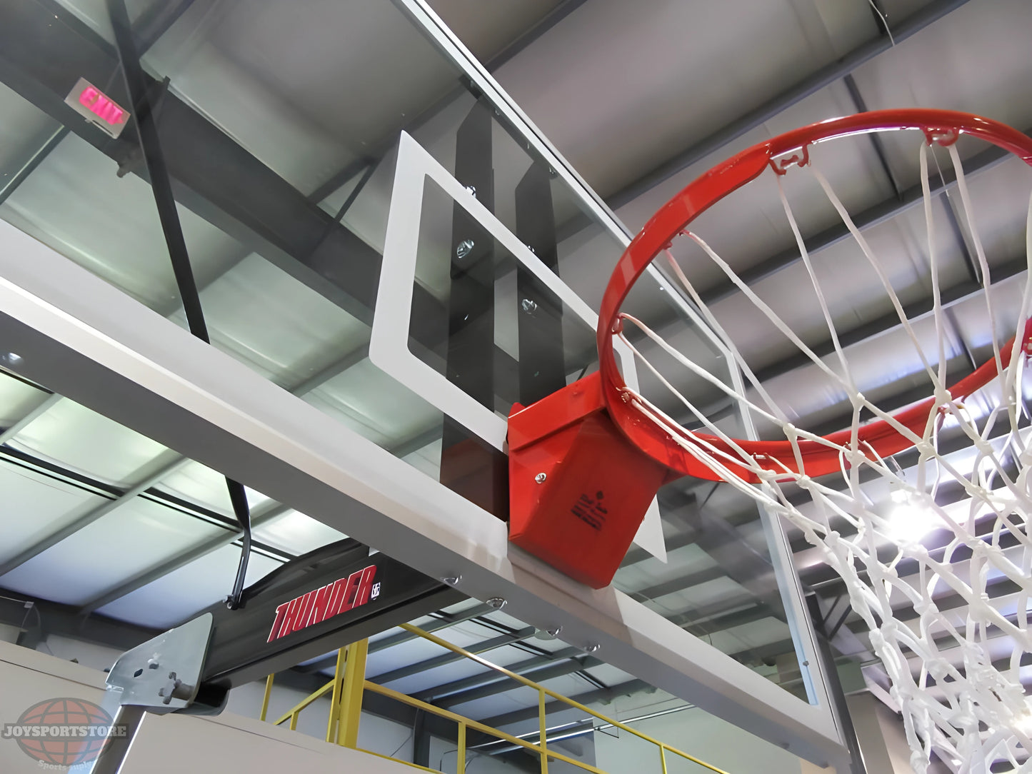 FIRST TEAM portable basketball hoop with clear backboard and red rim in indoor gym setting
