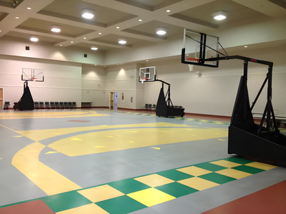 FIRST TEAM portable basketball hoop set up in indoor gym with multiple hoops and colorful court markings